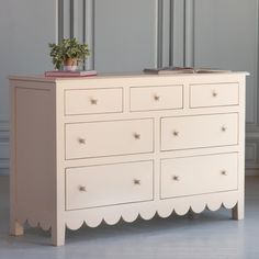 a white dresser with a potted plant sitting on it's top and bottom