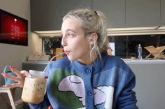 a woman sitting at a table with a drink in her hand