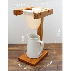 a wooden stand with a white pitcher on it and measurements for the cup in front