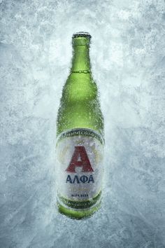 a bottle of beer sitting on top of snow covered ground with water splashing around it