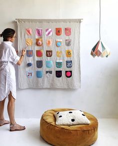 a woman standing in front of a wall hanging on the side of a white wall