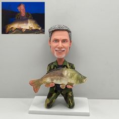 a bobble head figure holding a fish in front of a man's face