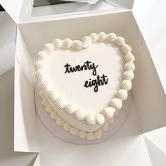 a heart shaped cake with the words twenty eight written on it, in a box