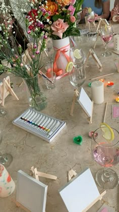 a table topped with lots of vases filled with different types of flowers and paintings