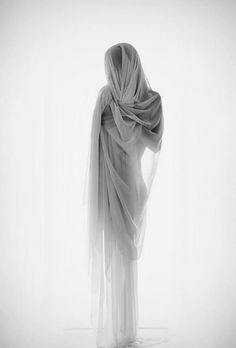 black and white photograph of a woman with veil on her head, back to the camera