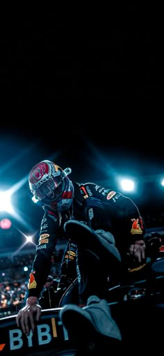 a man riding on the back of a motorcycle in front of a stadium filled with people