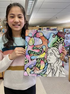 a girl holding up a painting in a library