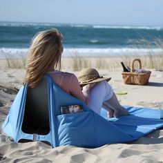 a woman sitting in a chair on the beach with her back to the camera, looking out at the ocean