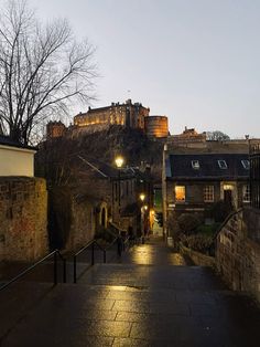 an alley way leading to a castle with lights on it's top and bottom