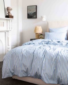 a bed with blue and white striped comforter next to a fireplace in a bedroom