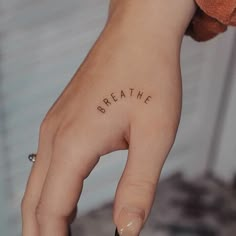 a woman's hand with the word breathe written on it, in cursive font