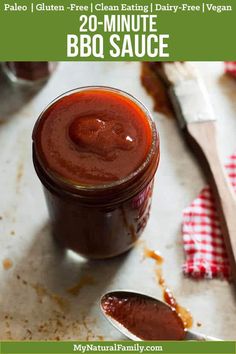 a jar of bbq sauce sitting on top of a table next to a spoon