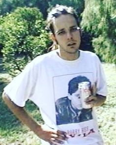 a man holding a drink in his right hand and wearing a t - shirt with an image on it