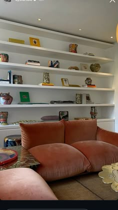 a living room filled with lots of furniture and bookshelves on the wall above