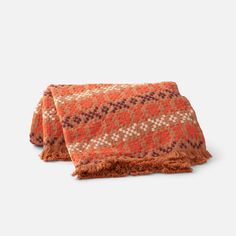 two orange and brown throw pillows on top of each other with fringes around the edges