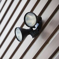 an outdoor light on the side of a building with wood slats in the background