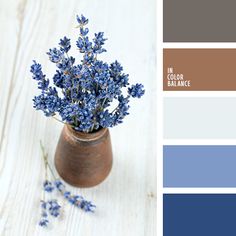 a vase filled with blue flowers sitting on top of a wooden table next to a color swatch