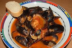 a bowl filled with clams and bread on top of a table