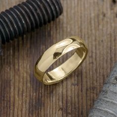 a silver ring sitting on top of a wooden table next to a knife and screwdriver