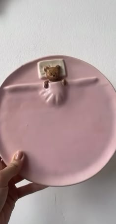 a person holding a pink plate with a teddy bear on the front and bottom part