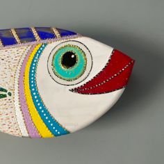 a ceramic fish with colorful designs on it's body and eyes painted on the side