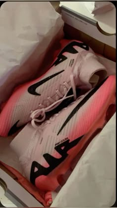 a pair of pink and black nike shoes in a box