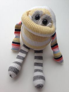 a stuffed animal with a striped scarf around it's neck and eyes, sitting on a white surface