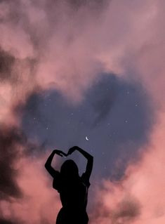 a woman standing in front of a heart shaped cloud with the moon above her head