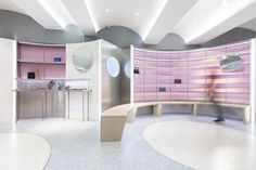 the interior of a beauty salon with pink and white walls, circular mirrors and benches