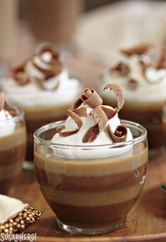 small desserts with whipped cream and chocolate toppings on a wooden tray, ready to be eaten