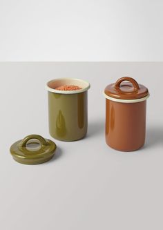 two ceramic containers with lids are sitting next to each other