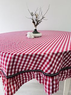 a red and white checkered table cloth with a vase filled with flowers on top