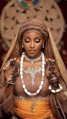 an african woman dressed in traditional garb and jewelry, with her hands on her chest