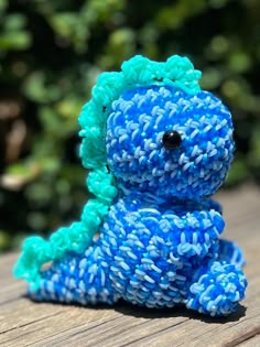 a blue and green stuffed animal sitting on top of a wooden table