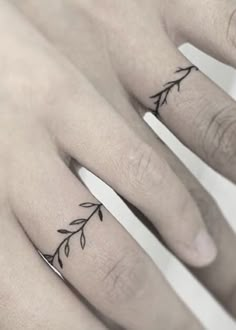 two fingers with small tattoos on them, one is holding the other's hand