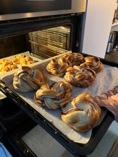 freshly baked pastries sit on baking trays in front of an oven