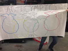 a man holding up a sign that says ac olympics