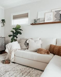 a living room with a white couch and some pictures on the wall next to it