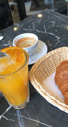 an orange drink and croissants on a table