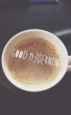 a cup of coffee with the words good morning written on it in white lettering, sitting on a black table