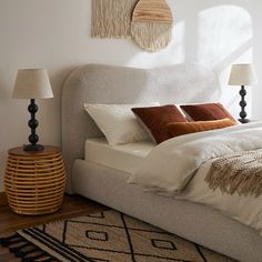 a bed with two lamps on either side of it and a rug in front of it