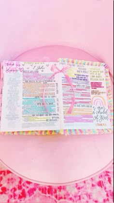 an open bible sitting on top of a pink plate