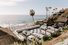 an outdoor dining area with chess board and palm trees on the beach next to the ocean