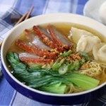 there is a bowl of soup with meat and vegetables on the table next to some chopsticks