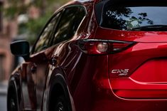 the rear end of a red mazda cx - 5 parked on a city street