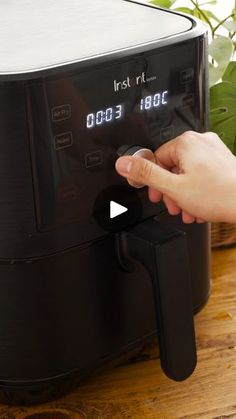 a person is pressing the button on an air fryer