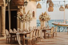 an outdoor dining area with tables and chairs set up for a formal function overlooking the ocean