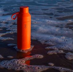 an orange water bottle sitting in the surf