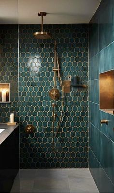 a bathroom with green tile and gold fixtures on the shower head, mirror, and sink