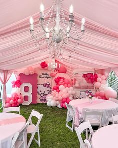 a hello kitty themed party with pink and white balloons, chandelier and tables